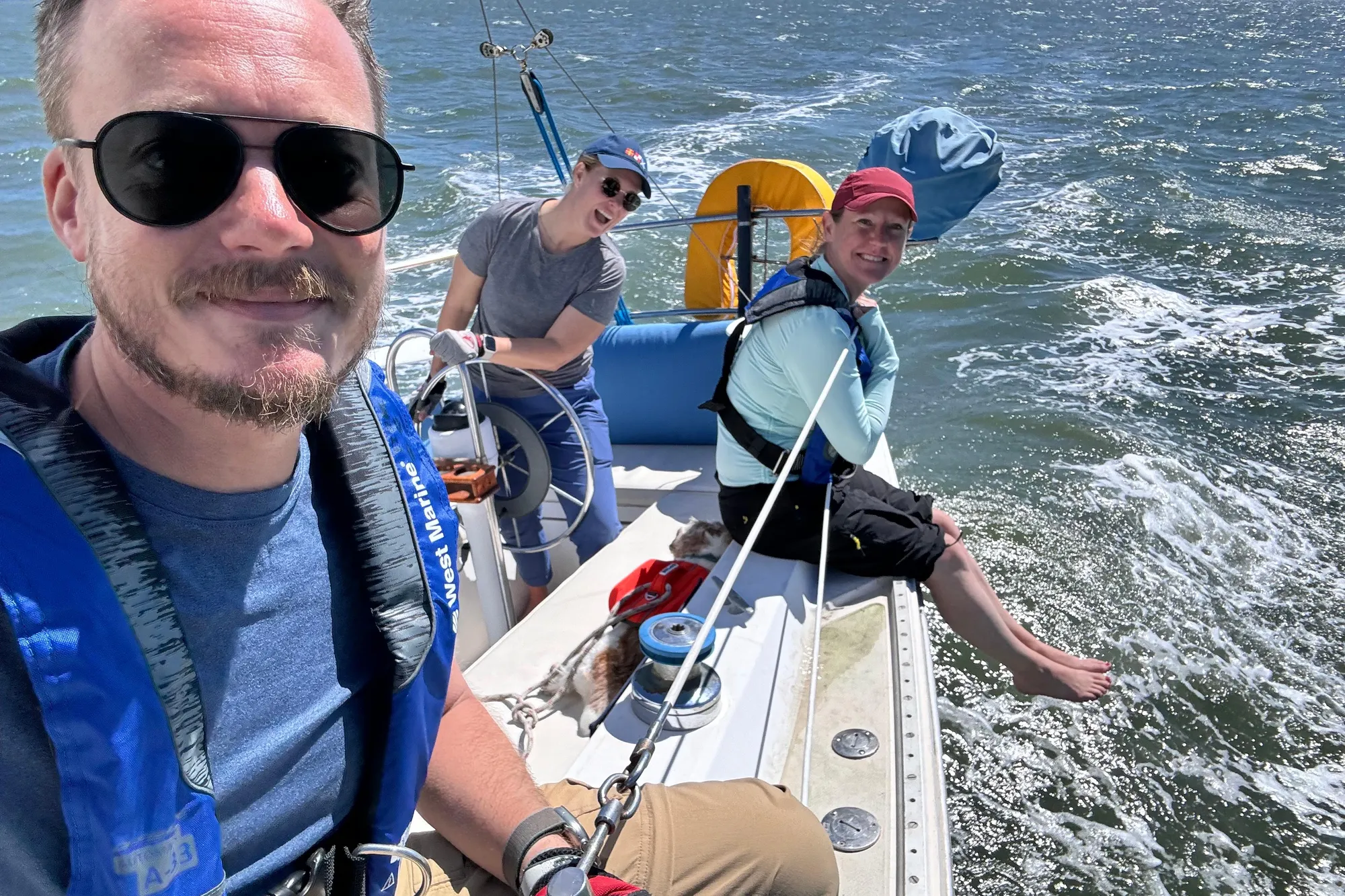 Three people enjoying a sunny day sailing on a 1980 Catalina 30 boat.