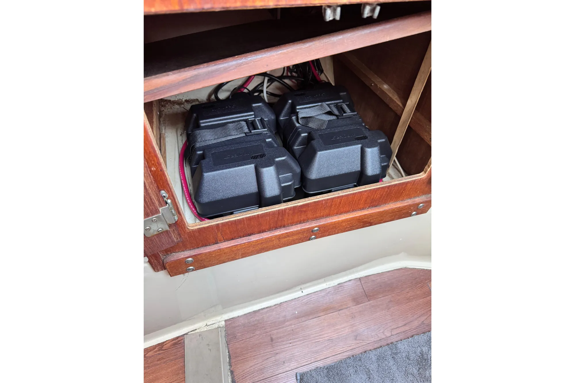 Battery compartment in a 1980 Catalina 30 sailboat with wooden cabinetry.