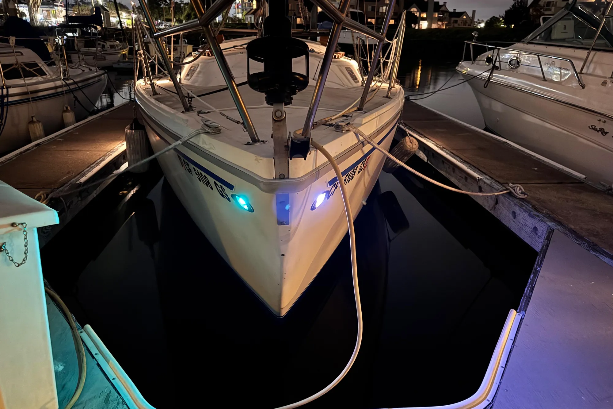1980 Catalina 30 sailboat docked at night with illuminated navigation lights.