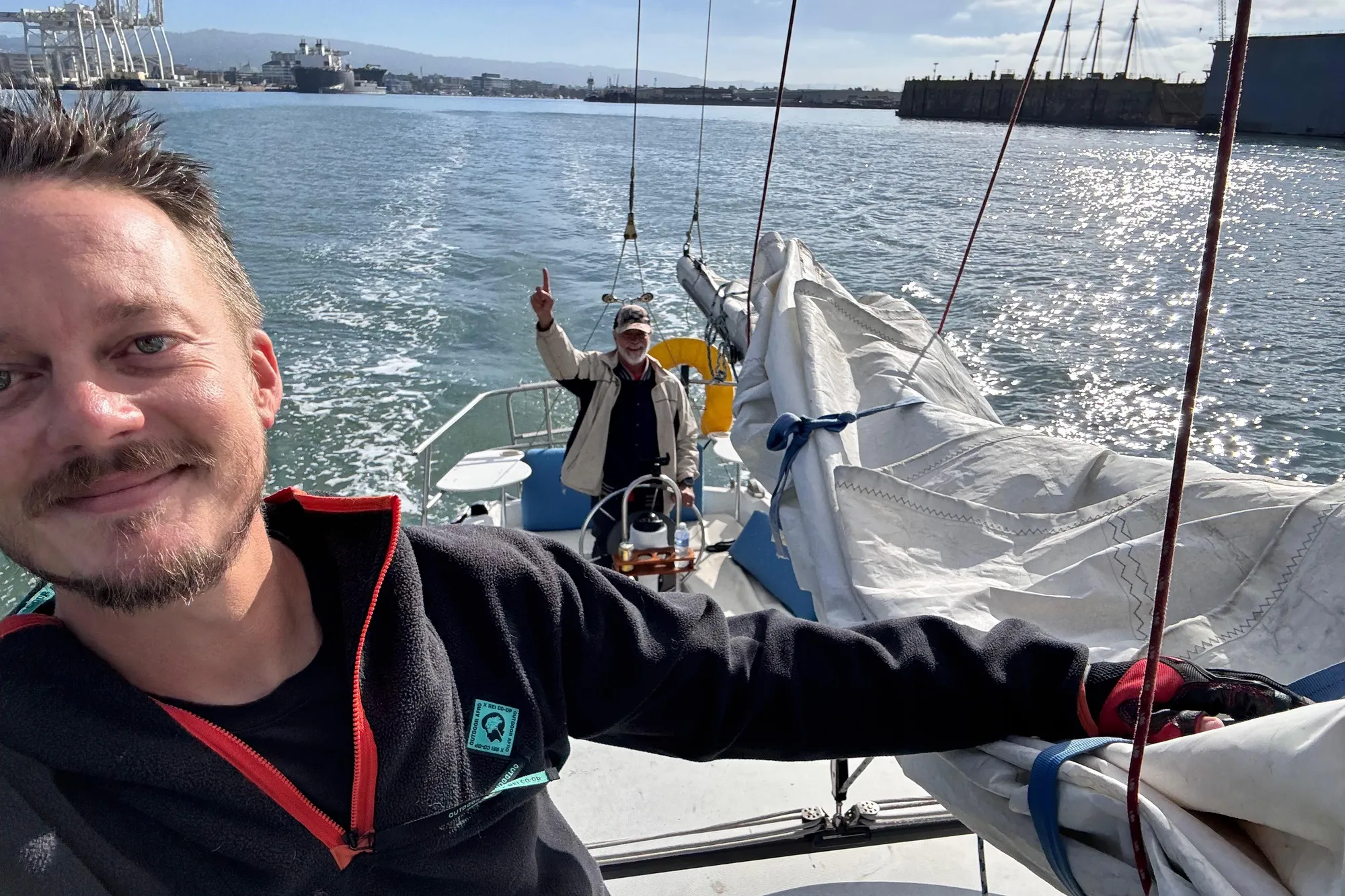 Two people sailing on a 1980 Catalina 30 boat in sunny waters.