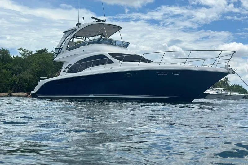  Yacht Photos Pics 2005 Sea Ray 500 Sedan Bridge yacht on water, with lush greenery in the background.