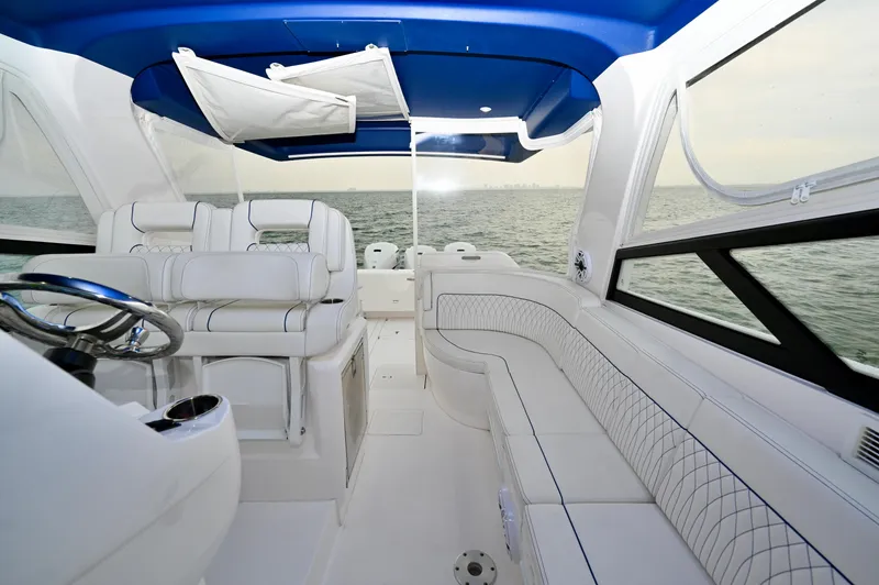  Yacht Photos Pics 2021 Intrepid 438 Evolution boat interior with white seating and blue canopy, overlooking the ocean.
