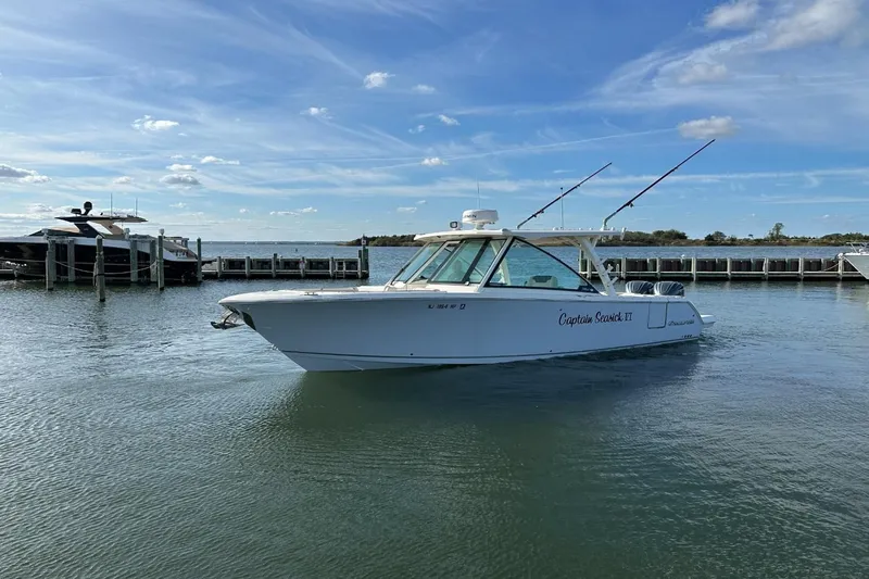  Yacht Photos Pics 2023 Sailfish 316 DC boat on calm water near a dock under a clear sky.