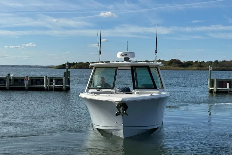  Yacht Photos Pics 2023 Sailfish 316 DC boat on calm water near a dock, under a clear sky.