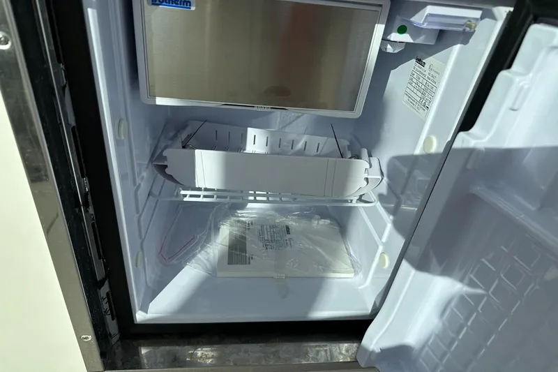  Yacht Photos Pics Open refrigerator inside a 2023 Sailfish 316 DC boat, showing shelves and manual.