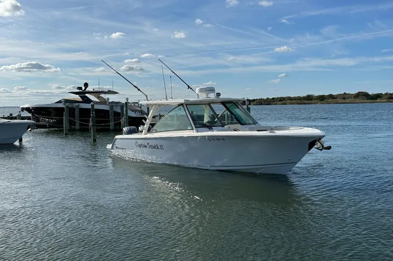  Yacht Photos Pics 2023 Sailfish 316 DC boat on calm water near a dock under a clear sky.