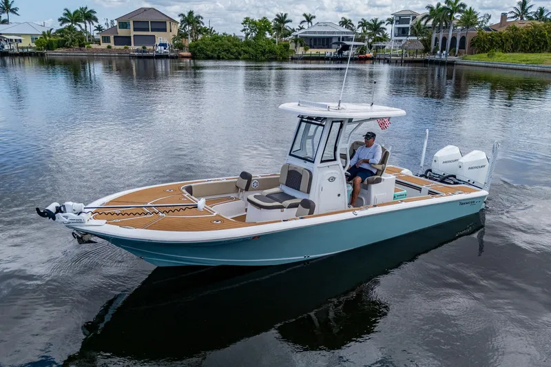  Yacht Photos Pics 2023 Tidewater 2700 Carolina Bay boat on calm water, surrounded by waterfront homes and palm trees.
