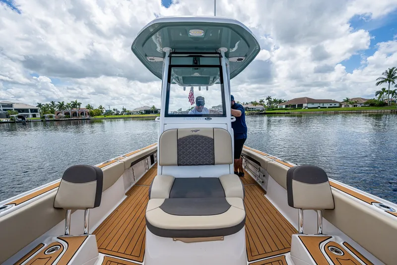  Yacht Photos Pics 2023 Tidewater 2700 Carolina Bay boat on a scenic waterway under a cloudy sky.