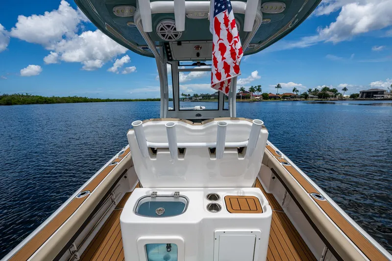  Yacht Photos Pics 2023 Tidewater 2700 Carolina Bay boat with fishing rod holders and American flag on calm water.