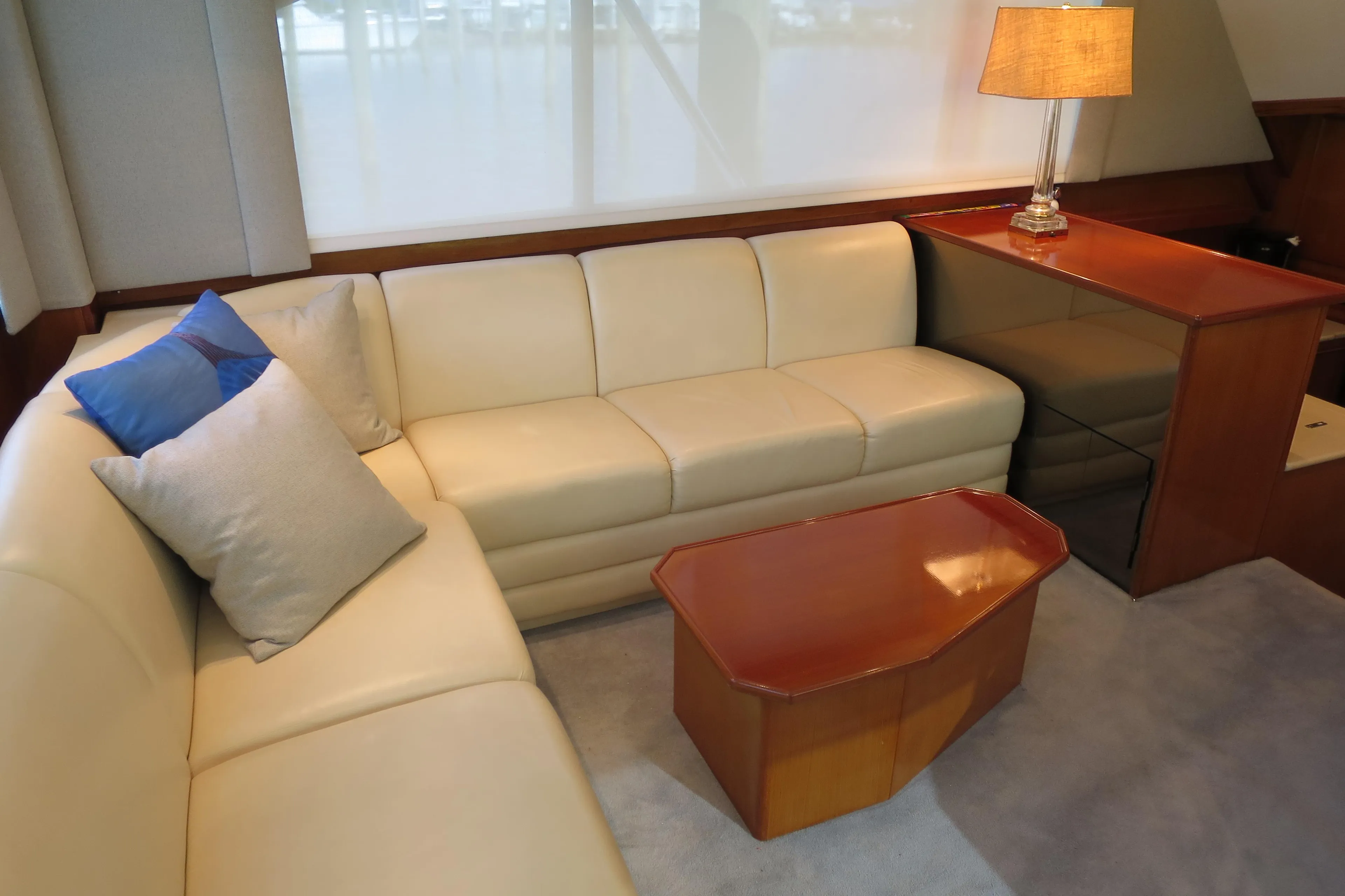 Luxurious 1997 Post 50 Flybridge yacht interior with cream leather sofa and wooden table.