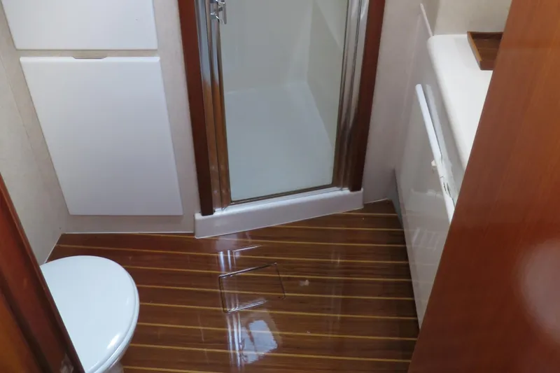 High Risk Yacht Photos Pics 1997 Post 50 Flybridge bathroom with shower, toilet, and wooden flooring.