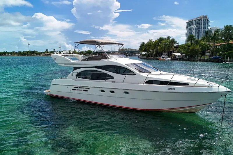  Yacht Photos Pics 2001 Azimut 46 yacht on clear blue water, with palm trees and buildings in the background.