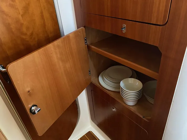 Magic Yacht Photos Pics Wooden cabinet with open door, displaying stacked white dishes and bowls. PDQ MV-41, 2008 model.