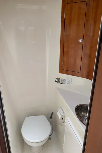 Magic Yacht Photos Pics Compact bathroom in 2008 PDQ MV-41 boat with toilet, sink, and wooden cabinet.
