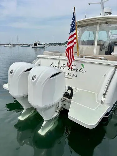 Fin & Tonic Yacht Photos Pics 2020 Back Cove 34O boat with dual outboard engines and American flag on calm water.