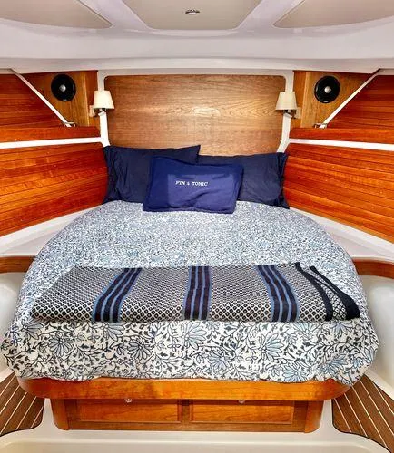 Fin & Tonic Yacht Photos Pics Cozy cabin interior of 2020 Back Cove 34O with wood paneling and patterned bedding.