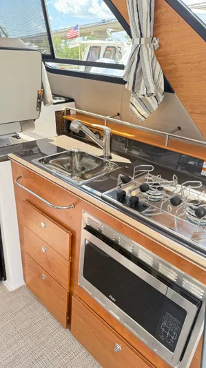  Yacht Photos Pics 2026 Cutwater C-288 Coupe kitchen with sink, stove, and microwave in a compact, modern design.