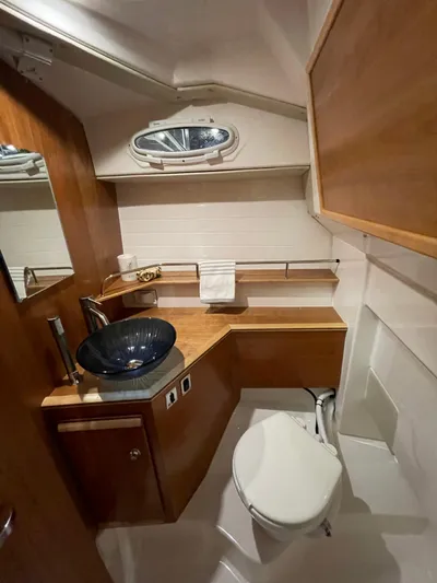  Yacht Photos Pics 2026 Cutwater C-288 Coupe bathroom with modern sink, wooden cabinetry, and porthole window.