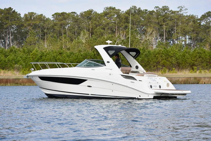  Yacht Photos Pics 2016 Sea Ray 310 Sundancer boat on calm water, surrounded by lush greenery.