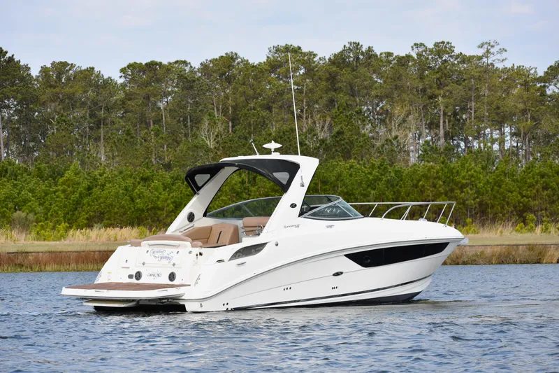  Yacht Photos Pics 2016 Sea Ray 310 Sundancer boat on a serene lake with forest backdrop.