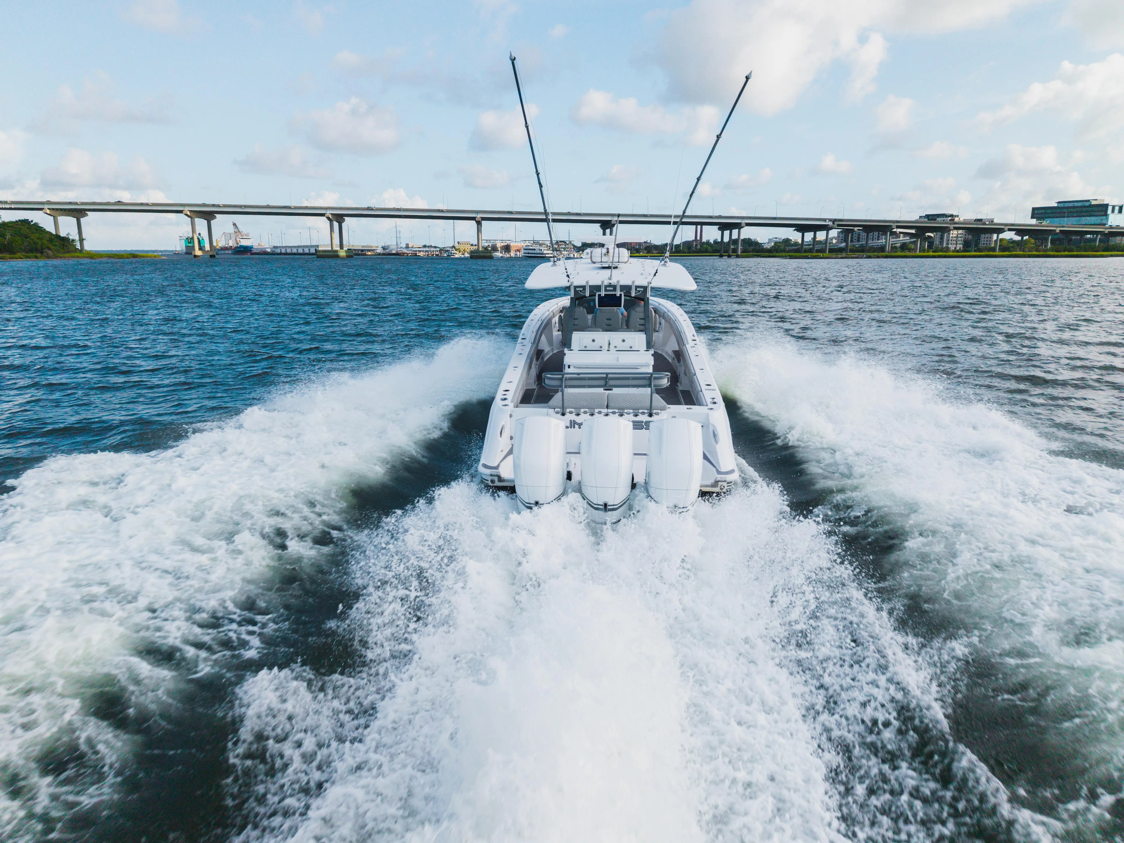  Yacht Photos Pics 2023 HCB 42 Lujo boat cruising on open water with bridge in background.