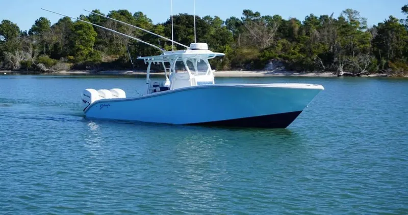  Yacht Photos Pics 2019 Yellowfin 34 boat cruising on calm water near a forested shoreline.