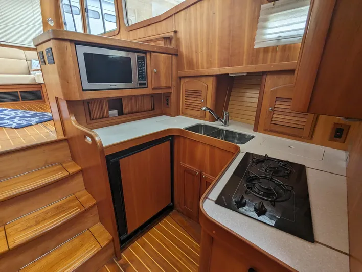  Yacht Photos Pics 2003 Sabre 36 Flybridge yacht kitchen with wood cabinetry, microwave, sink, and stove.