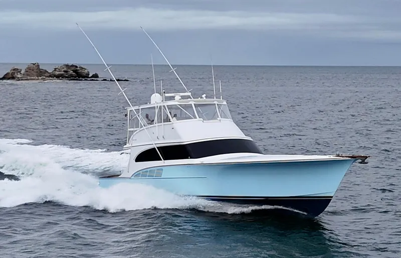  Yacht Photos Pics Custom Carolina 66 yacht cruising on the ocean, 2005 model, with rocky island in background.