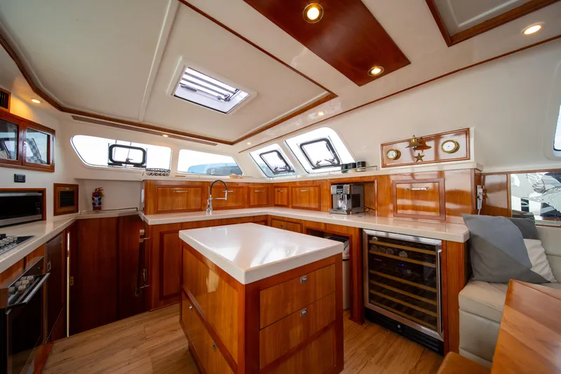 Walkabout Yacht Photos Pics Luxurious interior of 2019 Royal Cape Catamarans Majestic 530, featuring modern kitchen and elegant wood finishes.