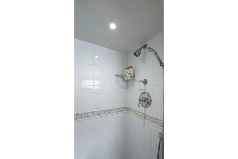 Stoneface Yacht Photos Pics Modern shower with white tiles, chrome fixtures, and built-in shelf for toiletries.