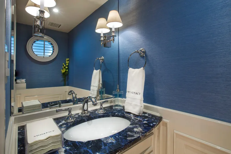 Stoneface Yacht Photos Pics Elegant bathroom with blue walls, marble countertop, and modern fixtures, featuring a round window.