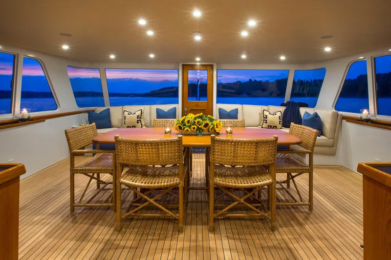 Stoneface Yacht Photos Pics Luxurious yacht interior with dining table, wicker chairs, and panoramic sunset views.