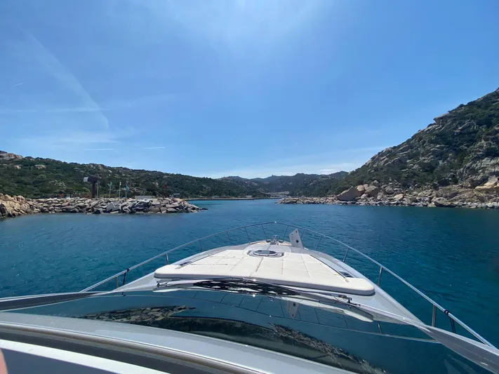 Good Vibes Yacht Photos Pics 2020 Pershing 62' yacht navigating through a scenic coastal inlet under a clear blue sky.