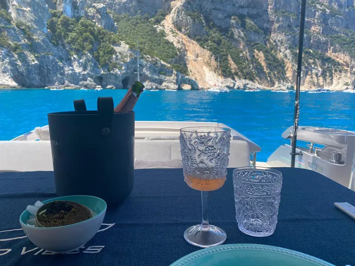 Good Vibes Yacht Photos Pics Luxurious dining setup on a 2020 Pershing 62' yacht with stunning coastal views.