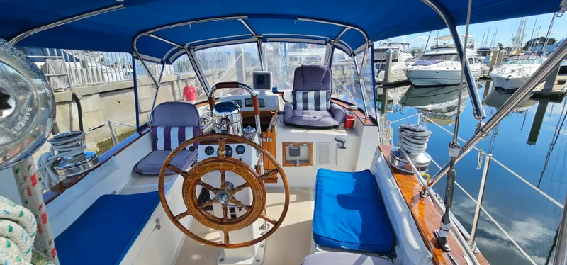 Burgoo Yacht Photos Pics 1980 Gulfstar 47 Sailmaster cockpit with blue cushions and wooden steering wheel, docked at marina.