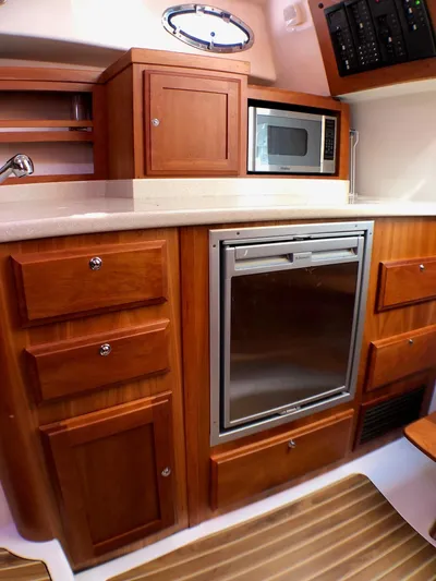 Lady In Blue Yacht Photos Pics 2012 Back Cove 30 yacht kitchen with wooden cabinets, microwave, and refrigerator.