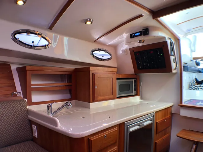 Lady In Blue Yacht Photos Pics 2012 Back Cove 30 yacht interior with kitchenette, featuring wood cabinetry, sink, and microwave.