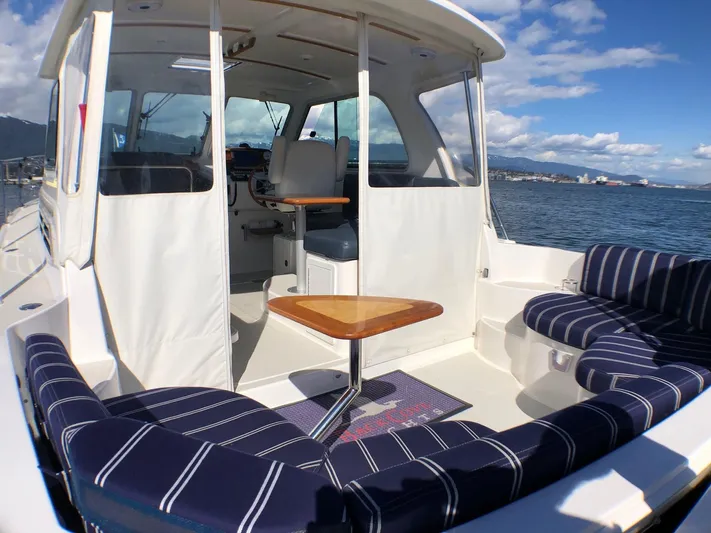 Lady In Blue Yacht Photos Pics 2012 Back Cove 30 boat interior with striped seating, wooden table, and ocean view.