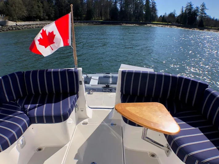 Lady In Blue Yacht Photos Pics Back Cove 30 boat, 2012 model, with Canadian flag, striped seating, and wooden table on calm water.