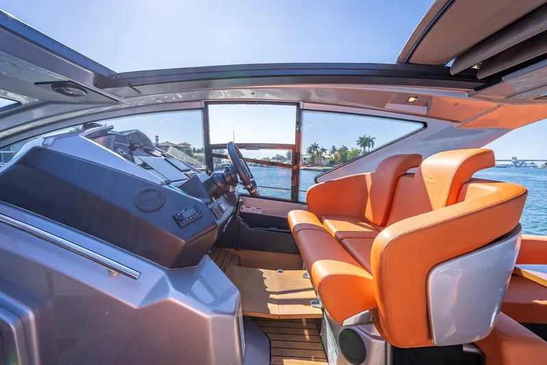 Namaste Yacht Photos Pics 2021 Cranchi M44 yacht interior with orange seats and modern dashboard, under a clear blue sky.
