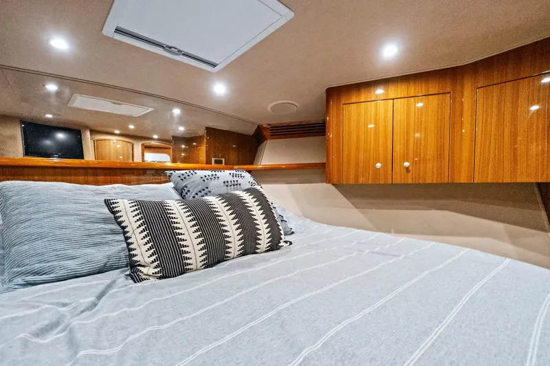  Yacht Photos Pics Luxurious cabin interior of 2008 Viking 74 Enclosed Bridge yacht with cozy bedding and wooden cabinets.