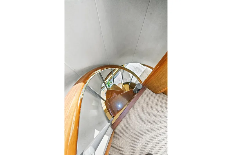  Yacht Photos Pics Spiral staircase inside 2008 Viking 74 Enclosed Bridge yacht, featuring wooden and carpeted design.