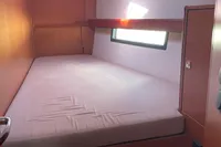 2020 Bavaria C45 yacht cabin with bed, window, and wooden interior.