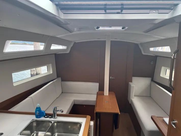 Resfeber Yacht Photos Pics Interior of 2023 Jeanneau Sun Odyssey 380 sailboat, featuring modern seating and a compact kitchen area.