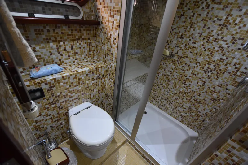 Vesuvio Yacht Photos Pics Compact bathroom with mosaic tiles, featuring a toilet and shower in a 2007 Pacific Prestige 170.