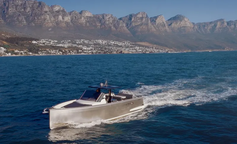 Hummingbird Yacht Photos Pics Fjord 40 Open yacht cruising on blue ocean with mountainous coastline in the background.