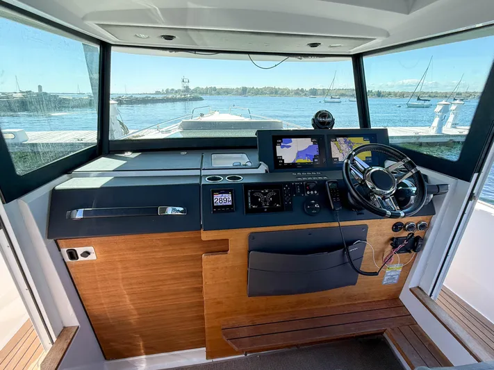 Essi Yacht Photos Pics 2019 Axopar 37 Cabin helm with navigation screens and steering wheel, overlooking marina.
