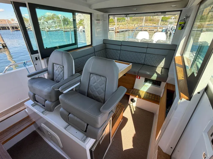 Essi Yacht Photos Pics 2019 Axopar 37 Cabin interior with gray seating and waterfront view.