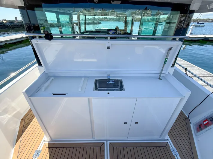 Essi Yacht Photos Pics 2019 Axopar 37 Cabin boat with outdoor kitchenette and sink, docked by the water.