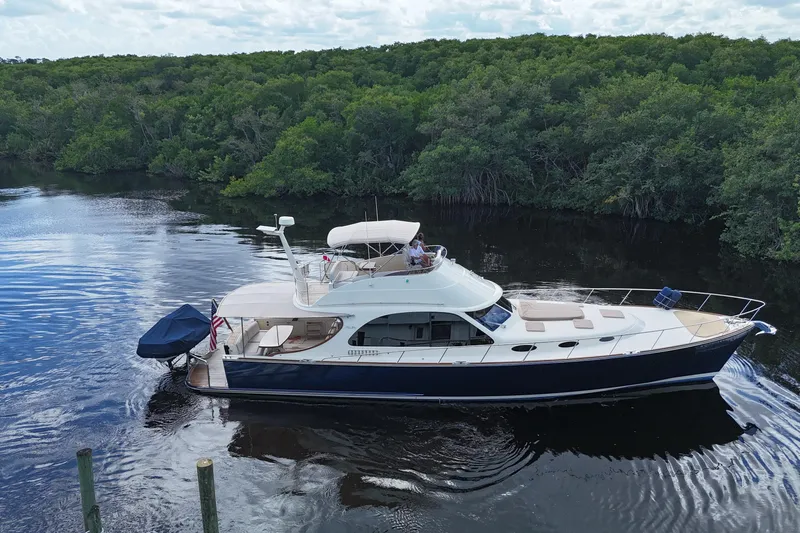 Tutto Bene Yacht Photos Pics 2018 Palm Beach Motor Yachts PB55 Flybridge cruising on a serene river, surrounded by lush greenery.